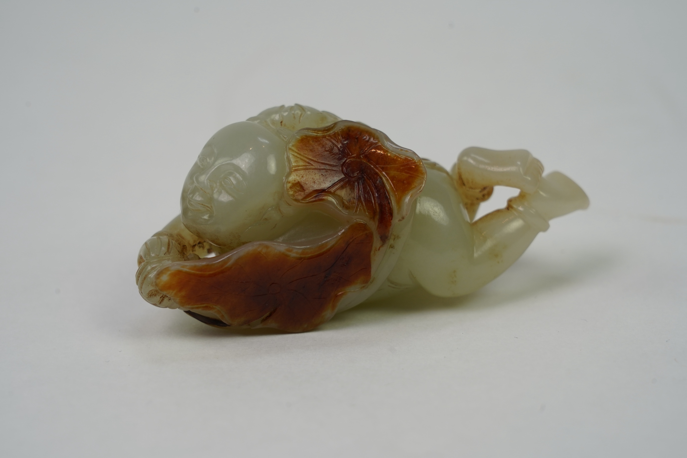 A Chinese pale celadon and russet skin jade figure of a boy and lotus